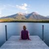 woman relaxing on jetty looking at mountains
