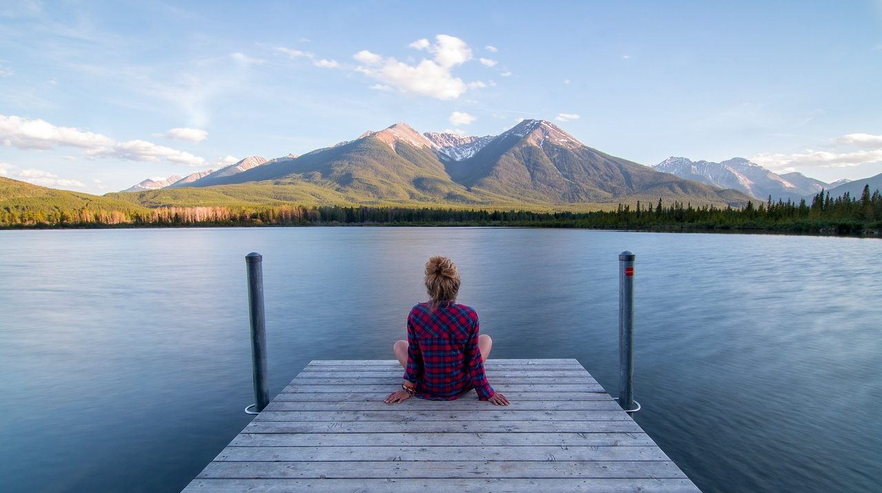 woman relaxing on jetty looking at mountains