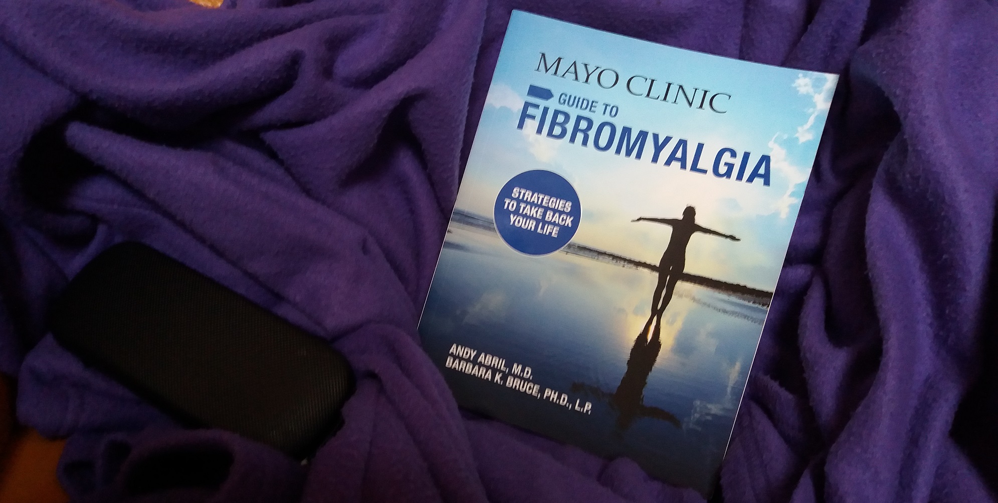 Mayo clinic guide to fibromyalgia on a blanket with glasses case