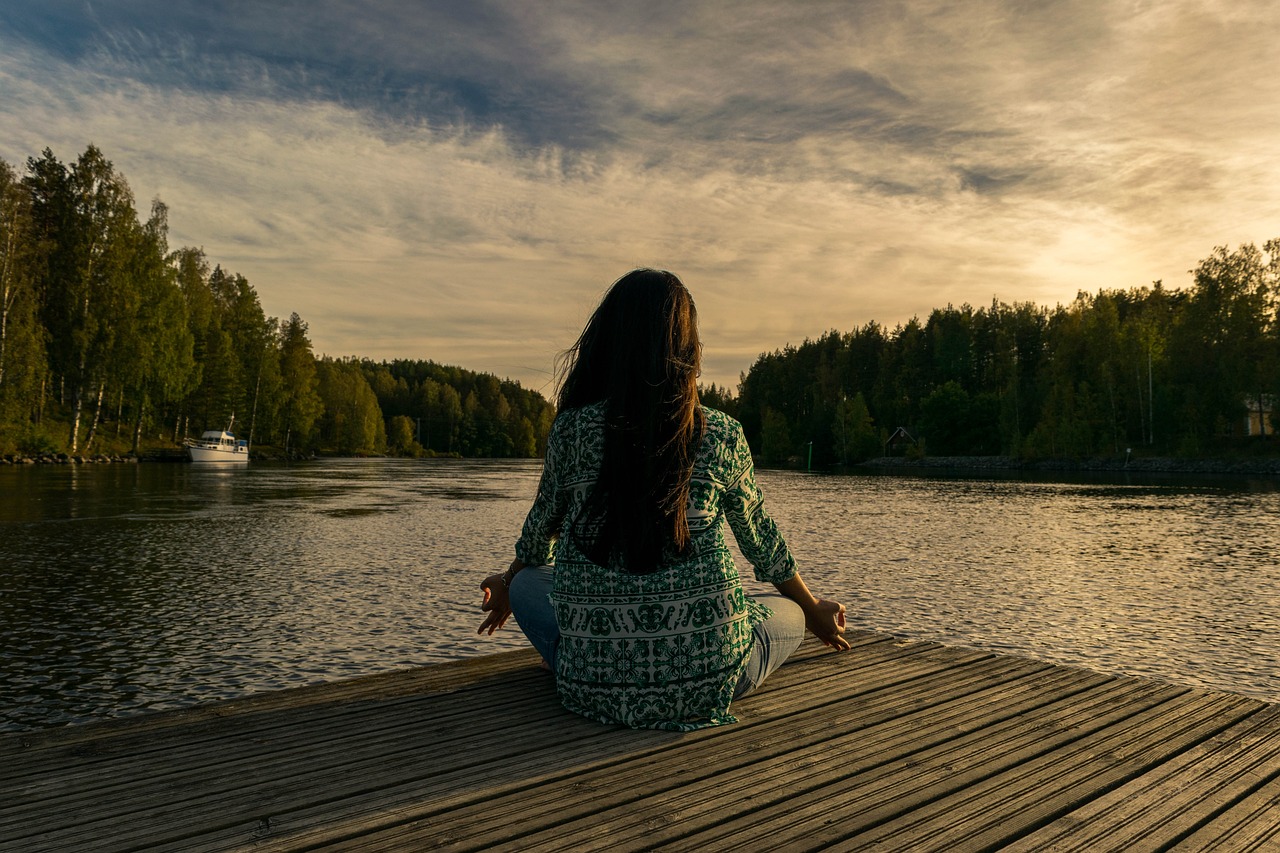 woman meditating in nature in front of a lake